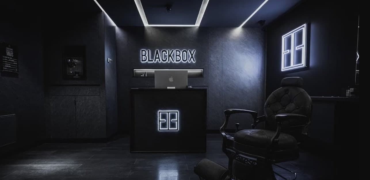 Le salon BLACKBOX : le comptoir d’accueil et son enseigne lumineuse.